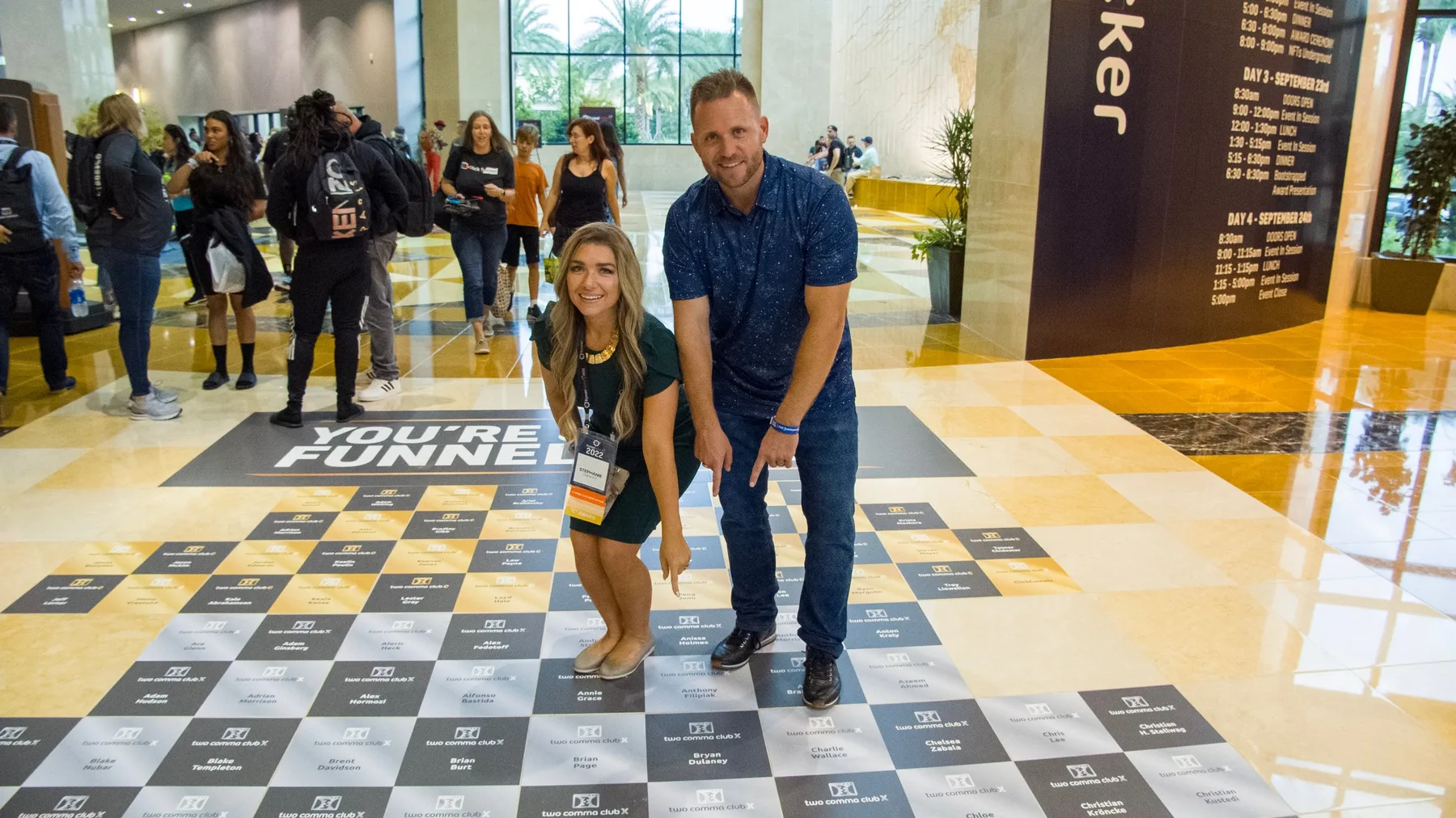Bryan and Stephanie Dulaney pointing to their names among the Two Comma Club X winners on the floor at Funnel Hacking Live